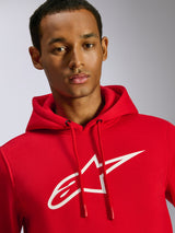 Sweat à capuche Alpinestars Ageless V3, rouge, avec grand logo Alpinestars blanc sur la poitrine, capuche à cordon de serrage avec embouts trempés, vêtement streetwear décontracté inspiré des sports mécaniques, porté par un mannequin homme