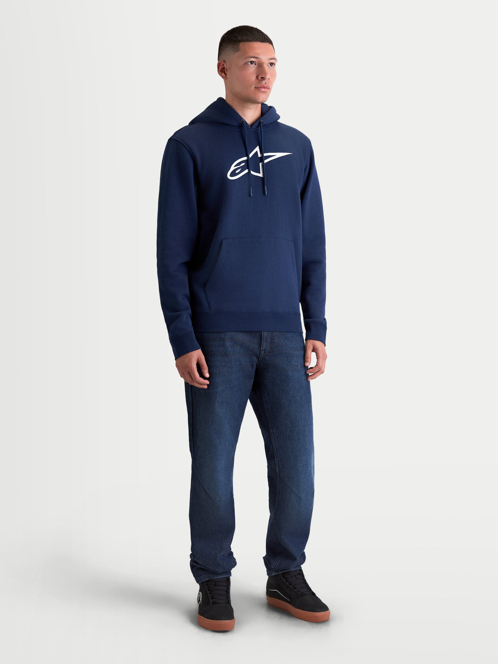 Alpinestars sweat à capuche Ageless V3, sweat à capuche sportswear pour homme, bleu marine et blanc, porté par un homme, avec logo Alpinestars blanc brodé à l'avant, polaire douce, capuche à cordon de serrage et poche kangourou.