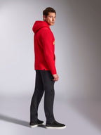 Sweat à capuche Alpinestars Ride V3, vêtement sportswear décontracté, rouge avec marquage jaune haute visibilité, modèle masculin portant un sweat à capuche rouge avec un pantalon noir et des baskets, vue de profil, modèle en polaire à enfiler avec poignets et ourlet en côtes