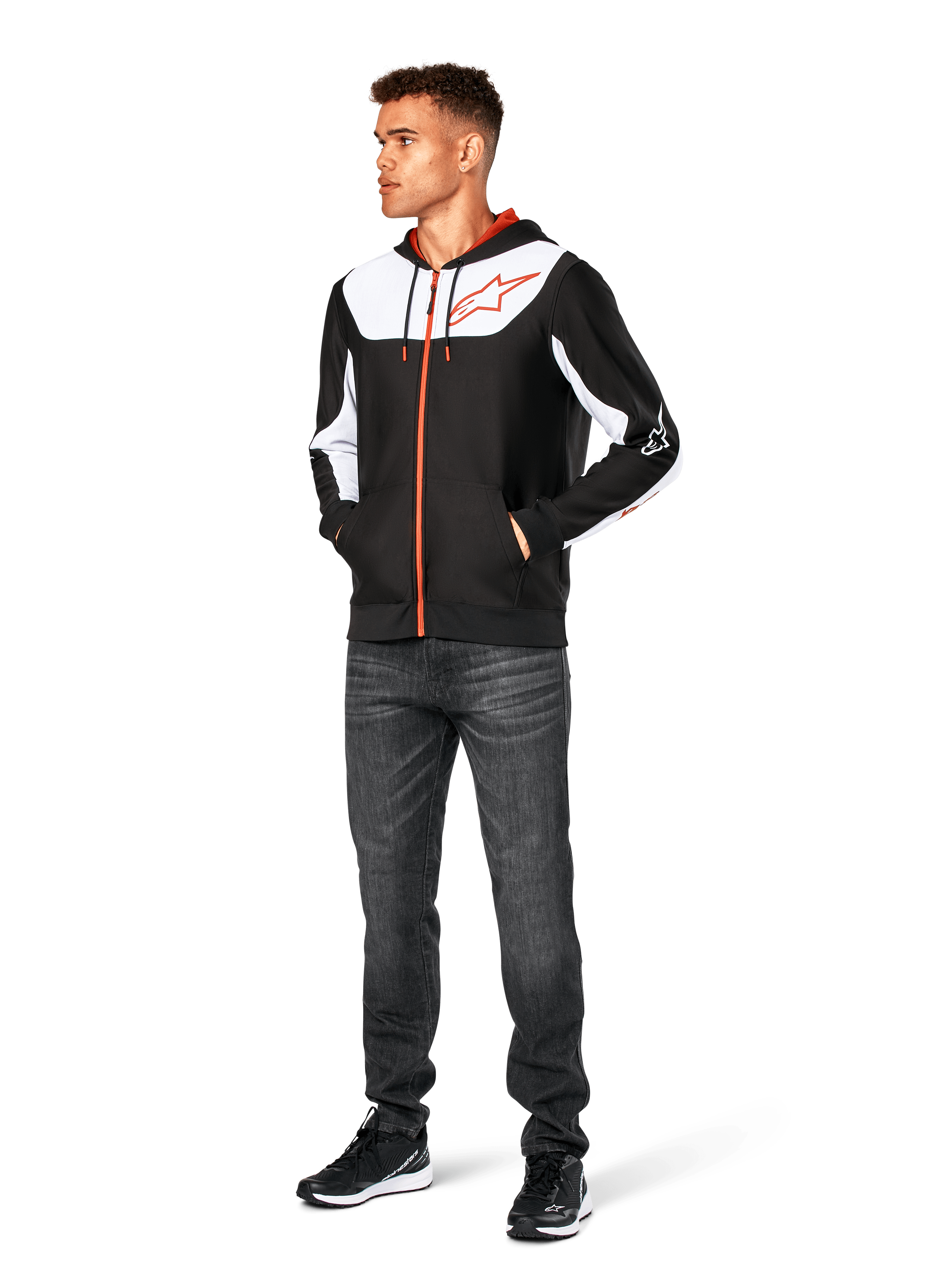 Sweat à capuche Alpinestars Sessions V3, sweat à capuche zippé décontracté, noir, blanc et rouge, porté par un mannequin avec un jean foncé et des baskets noires, doté d'empiècements blancs sur la poitrine et les manches, détails de fermeture éclair et cordons de serrage rouges, grand logo sur la poitrine, polaire en polyester au style streetwear inspiré du sport automobile