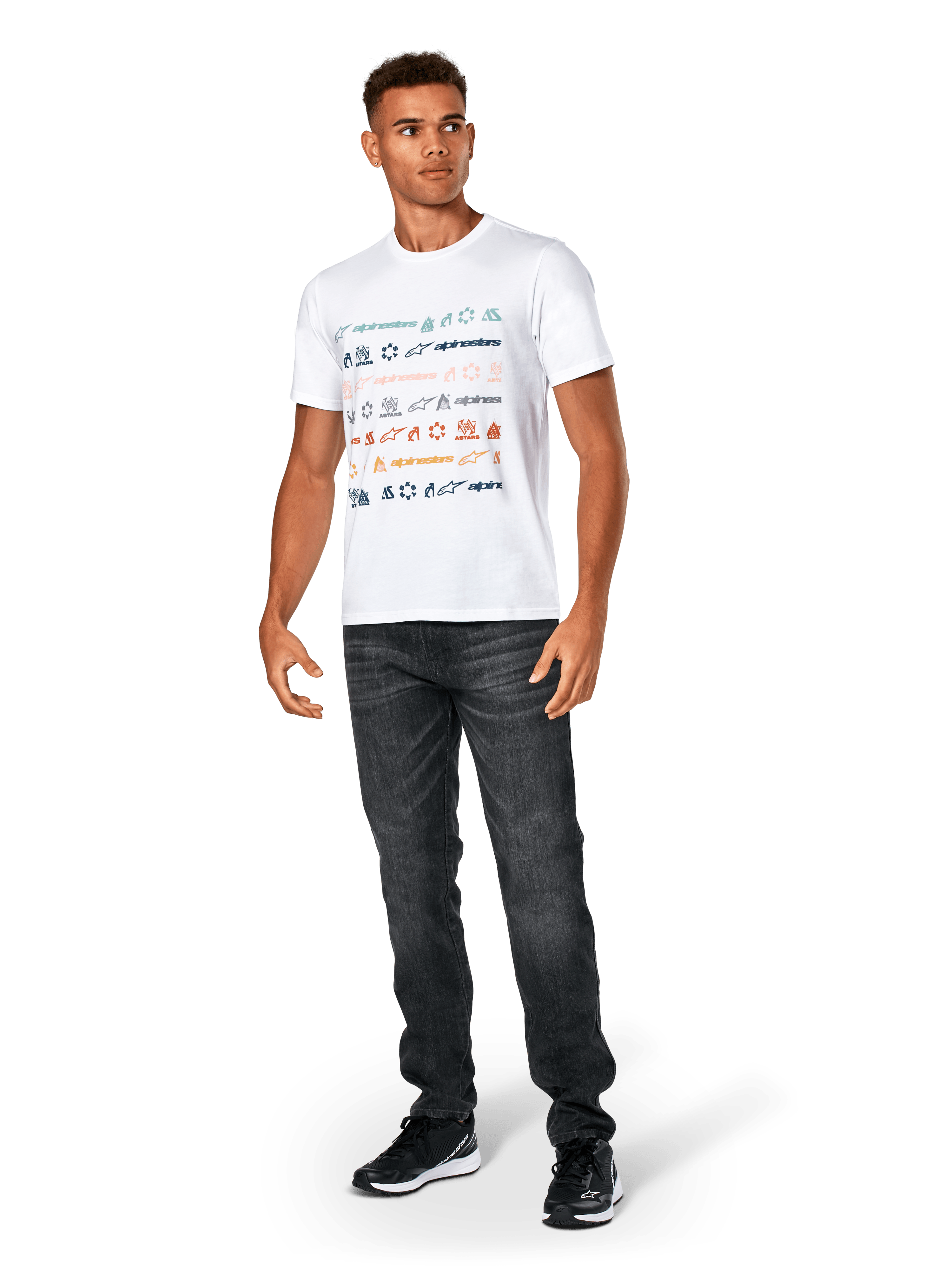 T-shirt Alpinestars Glyfs CSF, à manches courtes, blanc, avec graphique à rayures multi-logo sur le devant, porté avec un jean gris foncé et des baskets noires, vêtement sportswear décontracté inspiré du sport automobile