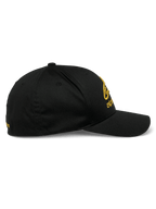 Casquette Alpinestars Gild, casquette sportswear, noir et or, vue de profil avec visière courbée, couronne structurée et broderie 3D métallique dorée sur le devant et le côté, tissu en sergé extensible