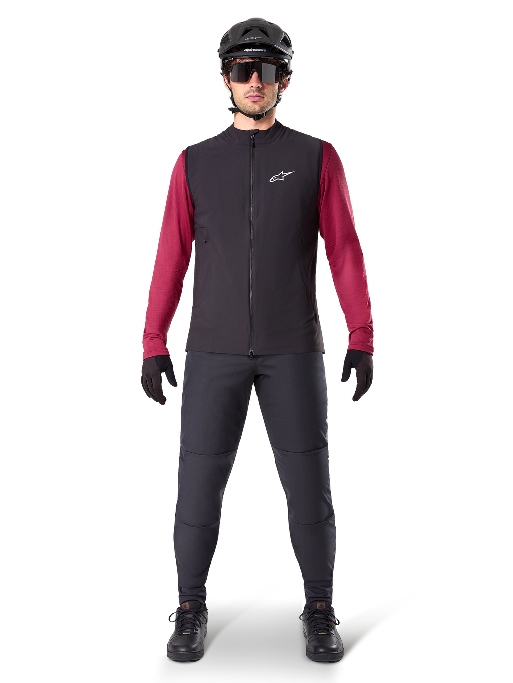 Gilet thermique Alpinestars A-Dura, gilet de cyclisme noir porté sur un maillot à manches longues bordeaux, associé à un pantalon de VTT gris foncé, casque et lunettes de soleil noirs, vêtement technique de VTT pour rouler par temps froid