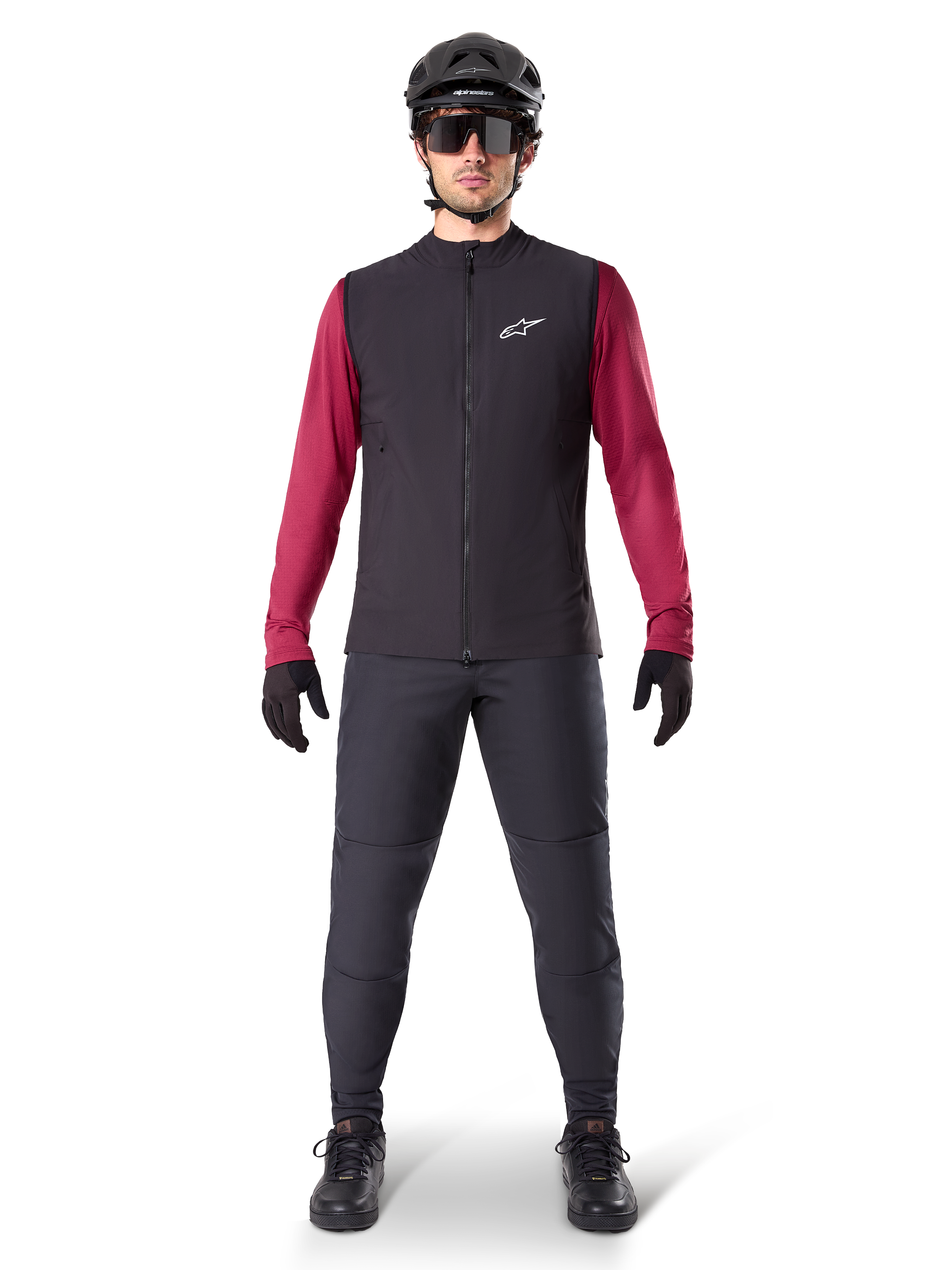 Gilet thermique Alpinestars A-Dura, gilet de cyclisme noir porté sur un maillot à manches longues bordeaux, associé à un pantalon de VTT gris foncé, casque et lunettes de soleil noirs, vêtement technique de VTT pour rouler par temps froid