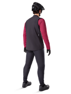 Gilet thermique Alpinestars A-Dura, gilet de cyclisme noir, vu de dos sur un modèle portant un maillot à manches longues bordeaux et un pantalon de cyclisme noir, associé à un casque de VTT et des gants noirs, équipement technique pour rouler par temps froid