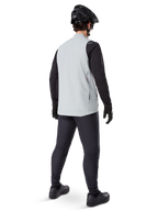 Alpinestars A-Dura Thermal Vest, Titanium Gray, rear view of model wearing the insulated cycling vest over a black long-sleeve top and dark pants, complete with a black mountain bike helmet and gloves, designed for cold-weather off-road riding