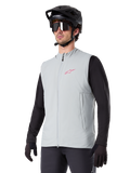 Alpinestars A-Dura Thermal Vest, Titanium Gray, cycling insulated vest, worn over a black long-sleeve shirt with a black mountain bike helmet and gloves, featuring a pink chest logo and vertical zippered side pockets