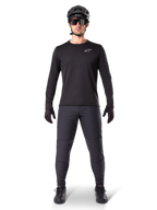Pantalon thermique Alpinestars A-Dura, noir, porté par un cycliste en tenue complète de VTT avec maillot noir à manches longues, casque et lunettes de soleil, pantalon durable à coupe régulière pour les sorties sur sentier par temps froid