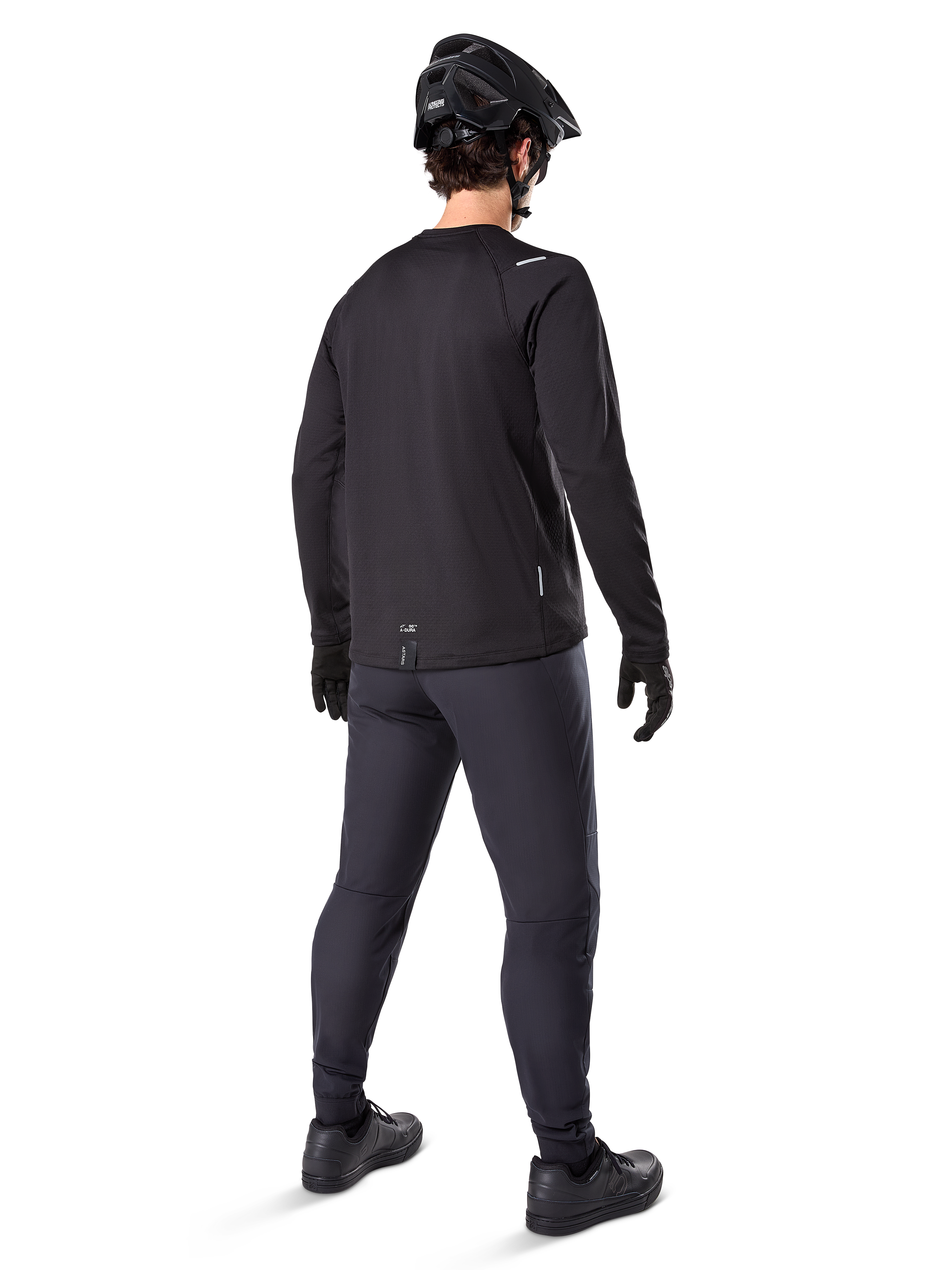 Pantalon thermique Alpinestars A-Dura, pantalon de VTT, noir, vu de dos, porté avec un maillot à manches longues assorti, un casque de VTT noir et des gants, équipement de cyclisme technique pour temps froid