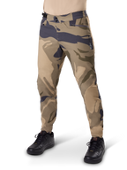 Alpinestars A-Dura Camo Pant, pantalon de cyclisme VTT, camouflage brun, doté d'une double fermeture à pression et de poches zippées, coupe régulière pour le VTT tout-terrain, porté avec des chaussures noires