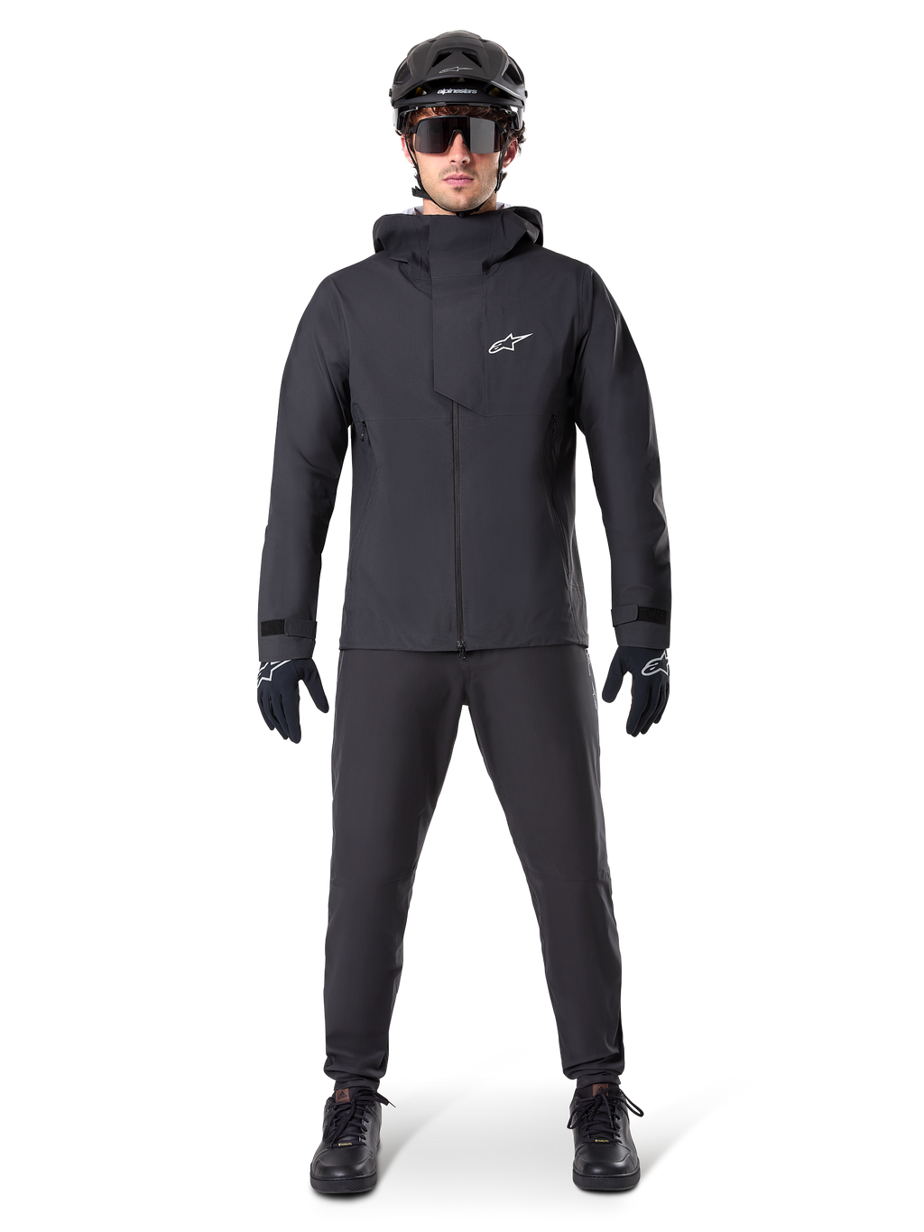 Pantalon imperméable Alpinestars A-Dura, pantalon de VTT noir, porté avec un équipement de VTT complet noir incluant une veste technique imperméable, un casque noir, des lunettes de soleil et des gants, conçu pour le tout-terrain par temps humide.