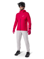Mannequin portant le pantalon imperméable Alpinestars A-Dura en gris Titanium, associé à une veste imperméable rouge vif, des gants assortis, un casque de VTT noir avec masque et des chaussures noires, équipement complet de VTT pour conditions humides