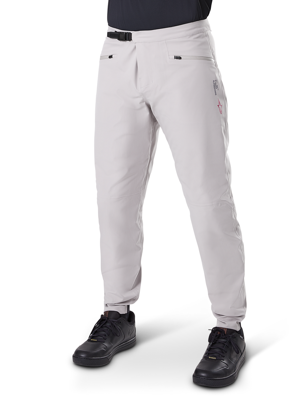 Pantalon imperméable Alpinestars A-Dura, pantalon de VTT, gris titane, doté d'une fermeture à cliquet noire à la taille et de poches zippées, jambes fuselées avec poignets élastiqués, porté avec des chaussures noires, construction imperméable 3L durable pour le cyclisme tout-terrain