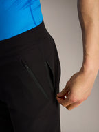 Short VTT Alpinestars A-Dura Ride noir, gros plan d'une main ouvrant une poche latérale zippée sécurisée.