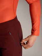 Shorts Alpinestars A-Dura Ride bordeaux, détail d'une main ouvrant la poche latérale zippée doublée de mesh.