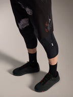 Shorts Alpinestars A-Dura Ride Black Camo, équipement VTT avec logo orange, genouillères et chaussures de vélo.