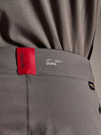 Pantalon Alpinestars A-Dura Elite, pantalon de VTT, gris foncé, gros plan sur la ceinture montrant une étiquette ASTARS rouge et un logo DURA blanc, doté d'un tissu Cordura texturé et de détails de marquage premium.