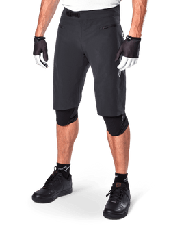 Alpinestars A-Aria Shorts, Mountain Biking Shorts, Black, knee-length with front zippered pockets and adjustable ratchet waist buckle, worn with black knee pads, socks, and cycling gloves