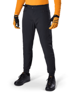Alpinestars A-Dura Pants, pantalon de VTT, noir, serrages latéraux à la taille et poches zippées, porté avec un maillot et des gants orange, coupe régulière sportive pour la pratique du VTT