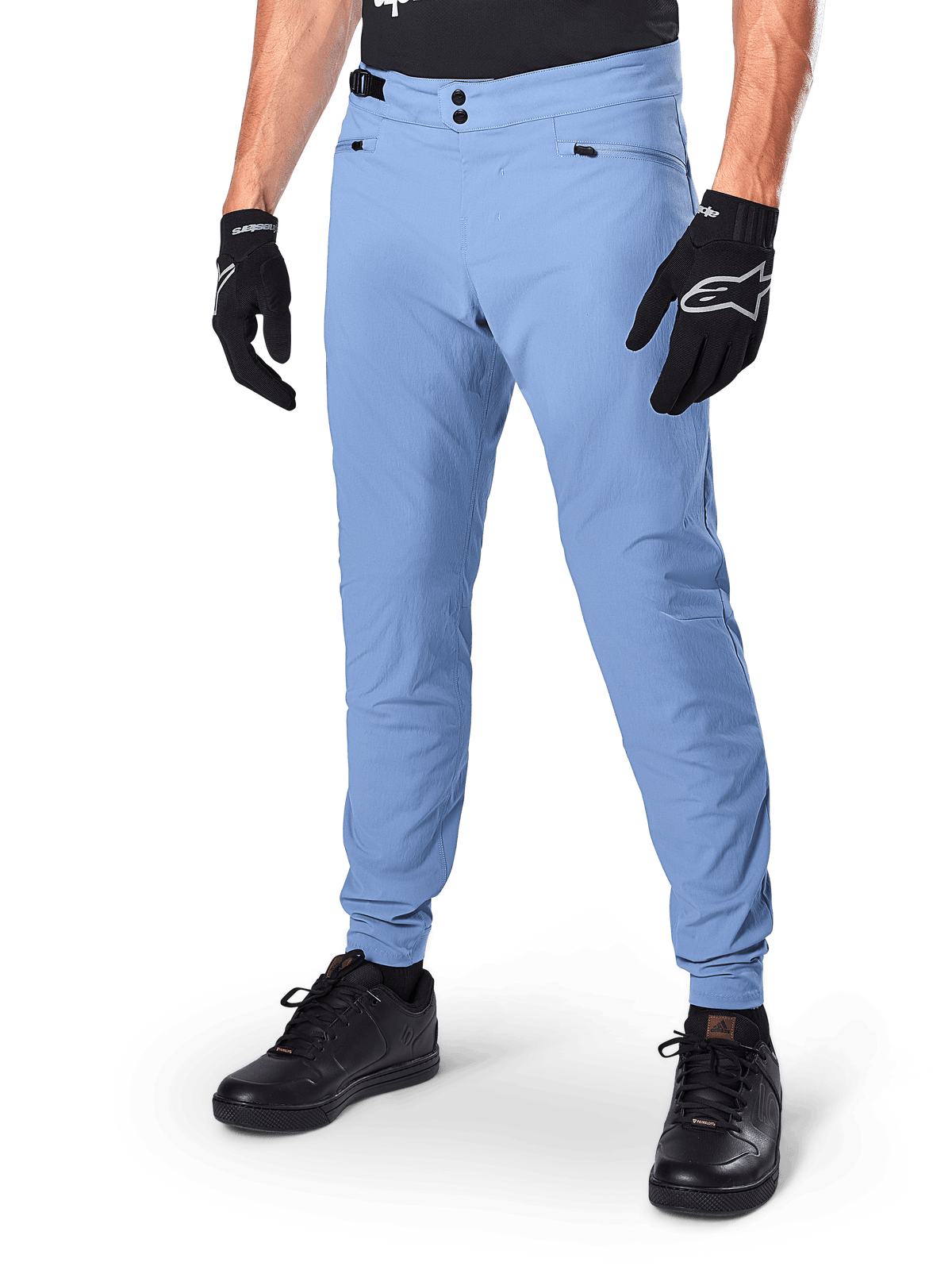 Pantalon Alpinestars A-Dura, pantalon de VTT bleu Infinity, doté d'une double fermeture à pression à l'avant et de poches zippées, porté avec des gants noirs et des chaussures noires, textile extensible 2 directions durable pour la pratique du tout-terrain