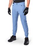 Alpinestars A-Dura Pants, Infinity Blue MTB Cycling Pants, featuring double snap front closure and zippered pockets, worn with black gloves and black shoes, durable 2-way stretch textile for off-road riding