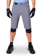 Short Alpinestars A-Dura, short de VTT, gris foncé, porté avec des gants et genouillères Alpinestars noirs, doté d'une double fermeture à pression et de poches zippées doublées en maille, tissu extensible 2 directions durable pour le cyclisme tout-terrain