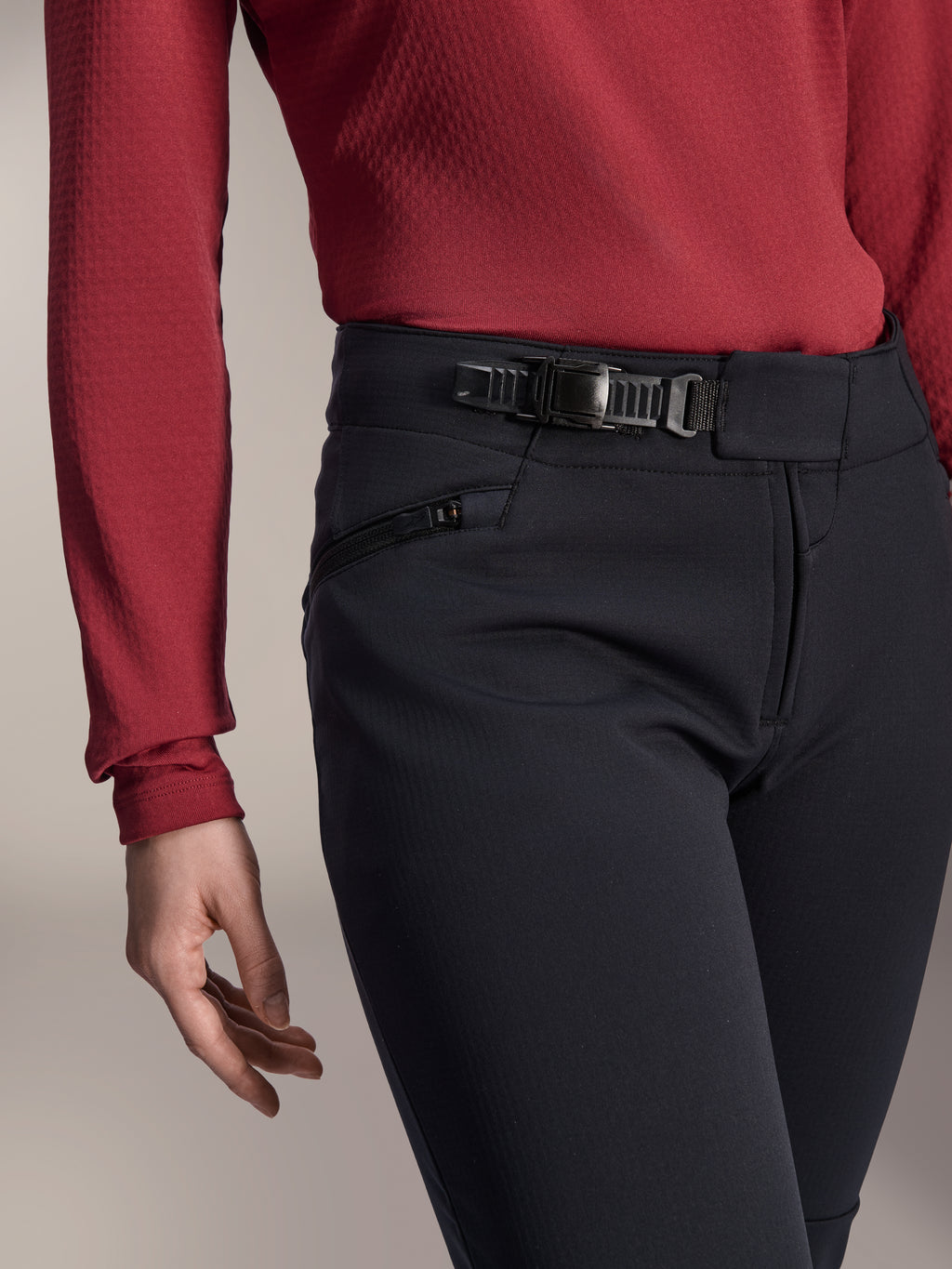 Alpinestars Stella A-Dura Thermal Pant, pantalon de VTT pour femme, noir, gros plan montrant le système de fermeture à cliquet sur la ceinture et la poche latérale zippée, porté avec un haut à manches longues rouge foncé, équipement durable pour le trail par temps froid