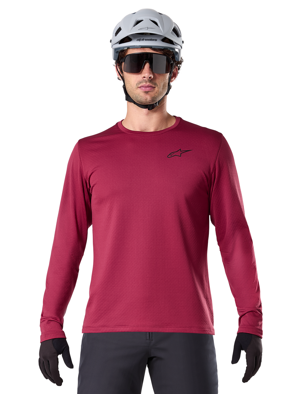 Maillot thermique Alpinestars A-Dura, maillot de VTT à manches longues pour homme, bordeaux, porté avec un casque gris et des lunettes de soleil noires, avec un petit logo étoile sur la poitrine, tissu polaire isolant pour le VTT par temps froid