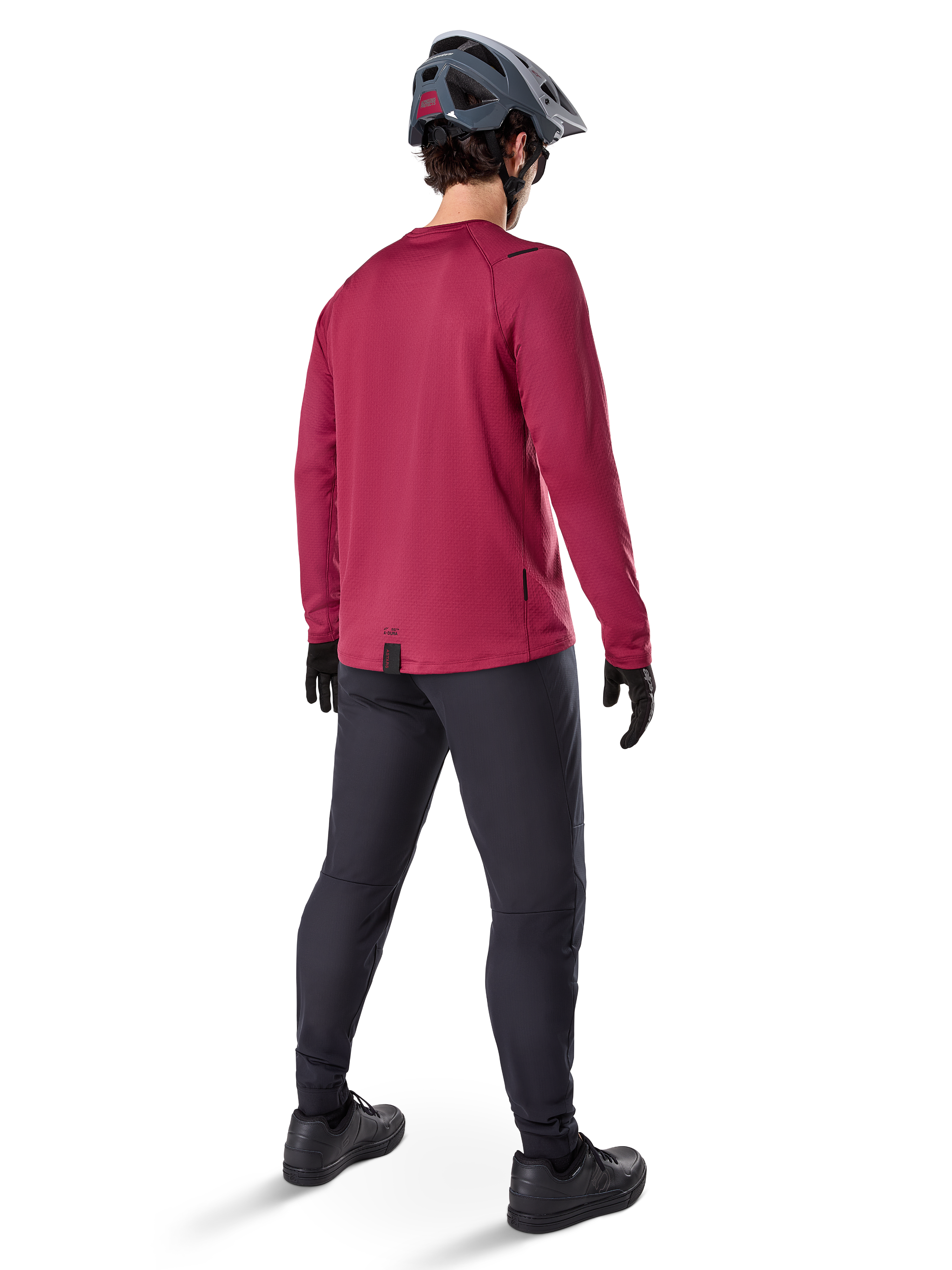 Alpinestars A-Dura Thermal Jersey, maillot de cyclisme à manches longues bordeaux, vue de dos, porté avec un pantalon de VTT noir et un casque gris, doté d'un pan arrière allongé pour une couverture arrière accrue, équipement de VTT pour temps froid
