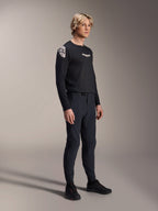 Model wearing Alpinestars A-Aria Polartec Elite Long Sleeve Jersey in Black, paired with matching black technical mountain bike pants and black shoes, performance cycling apparel for off-road riding, studio shot.