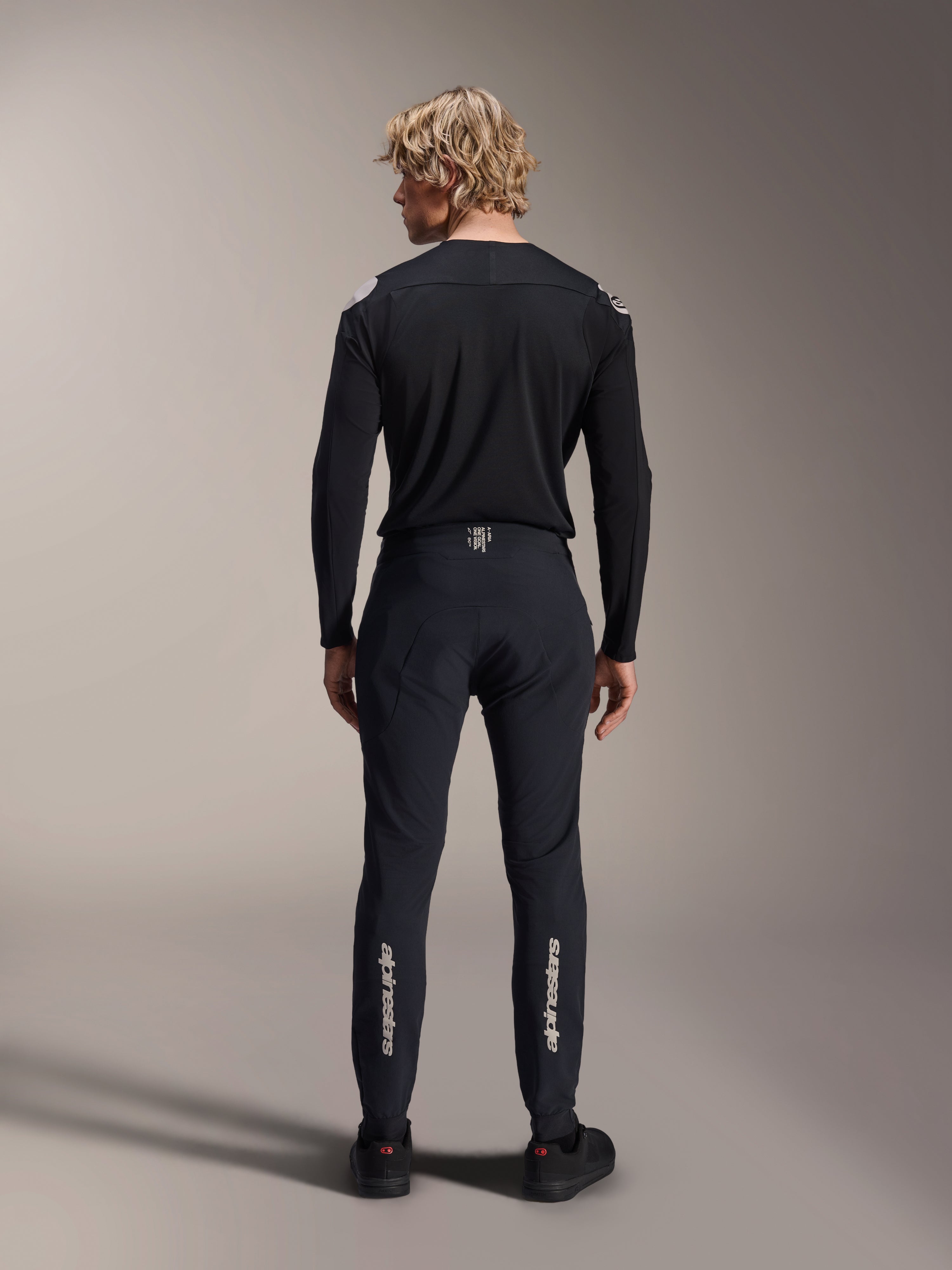 Alpinestars A-Aria Polartec Elite Long Sleeve Jersey, Black MTB Jersey, rear view worn with matching black pants, performance fit for mountain biking, featuring technical moisture-wicking fabric and subtle branding on the lower back