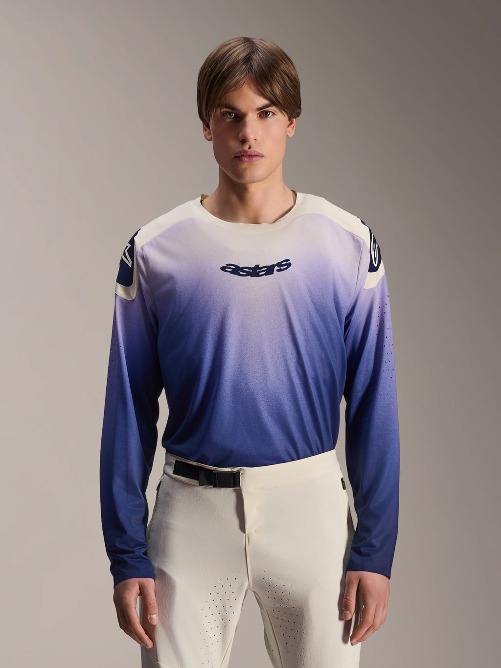 Alpinestars A-Aria Polartec Maker Elite Jersey, Long Sleeve MTB Jersey, Baja Blue with white-to-blue gradient, worn by a model with white pants, featuring dark blue chest logo and laser perforations on sleeves, performance mountain biking apparel