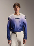 Alpinestars A-Aria Polartec Maker Elite Jersey, Long Sleeve MTB Jersey, Baja Blue with white-to-blue gradient, worn by a model with white pants, featuring dark blue chest logo and laser perforations on sleeves, performance mountain biking apparel