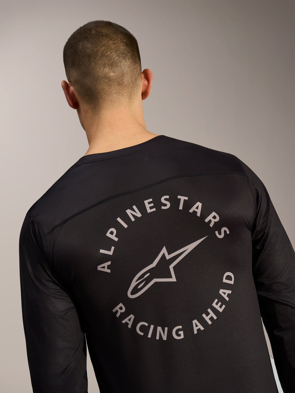 Maillot à manches longues A-Dura Air noir, logo circulaire Alpinestars Racing Ahead sur tissu mesh au dos.