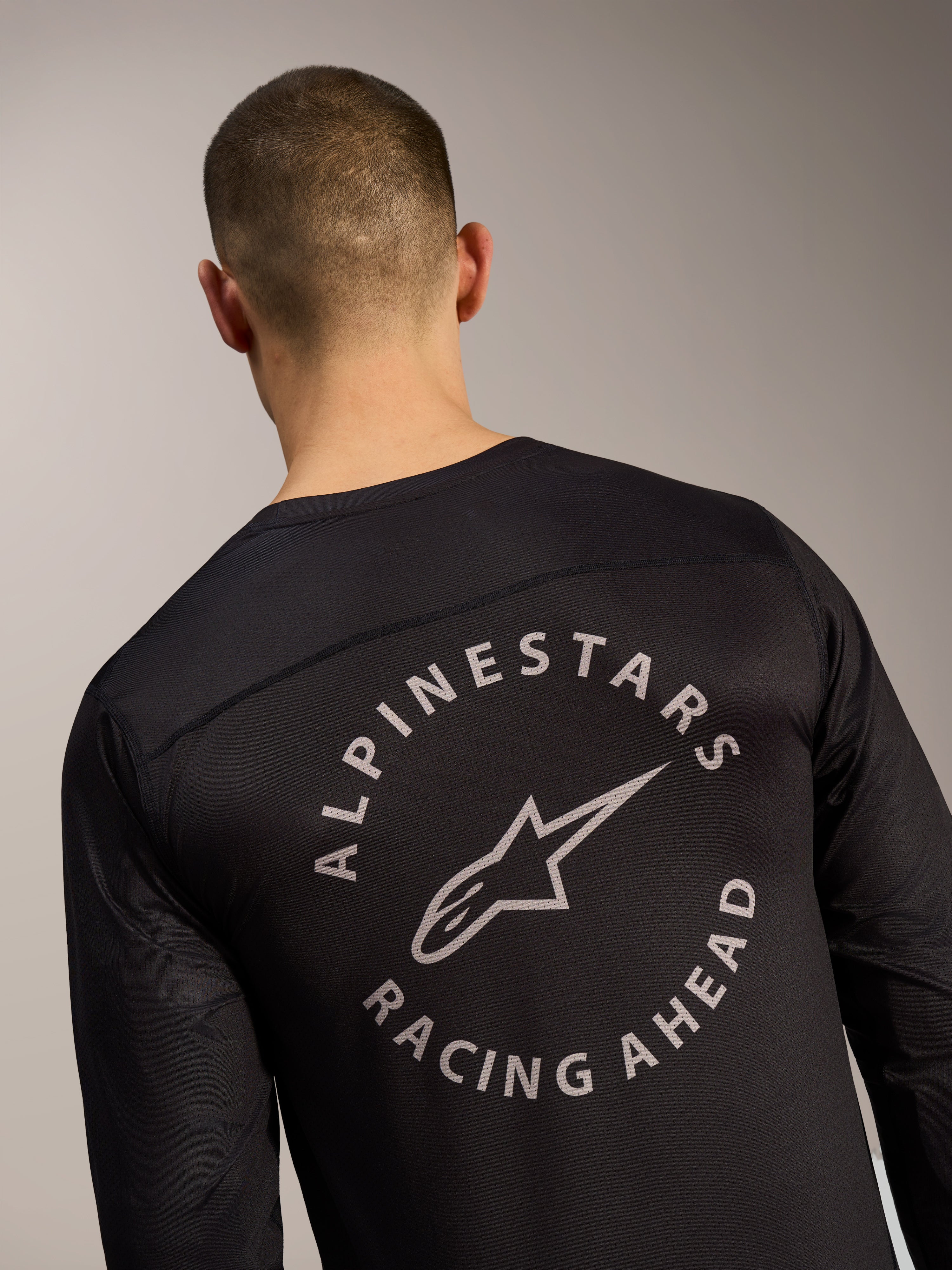 Maillot à manches longues A-Dura Air noir, logo circulaire Alpinestars Racing Ahead sur tissu mesh au dos.