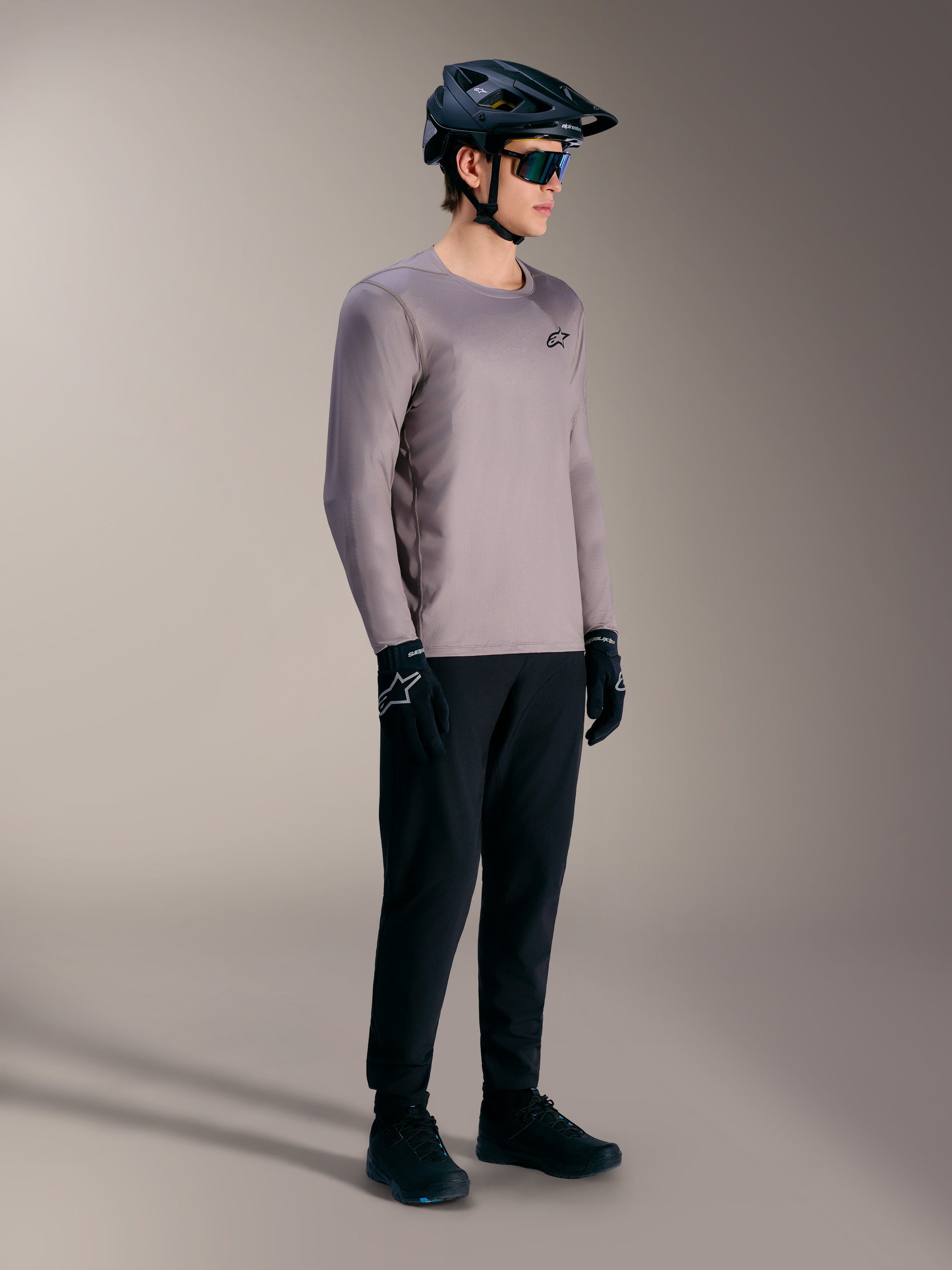 Alpinestars A-Dura Air Long Sleeve Jersey in gray, paired with a black MTB helmet and performance gear for trail riding.