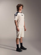 Maillot à manches courtes Alpinestars A-Aria Polartec Elite, écru avec empiècements noirs aux épaules et logo, porté par un mannequin avec un short assorti et des chaussures noires, vêtement de VTT haute performance pour la pratique sur sentiers.