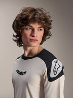 Maillot à manches courtes Alpinestars A-Aria Polartec Elite, écru avec empiècements noirs sur les épaules, arborant un logo Astars noir sur la poitrine et un logo Astars blanc sur l'épaule, équipement de VTT haute performance porté par un mannequin