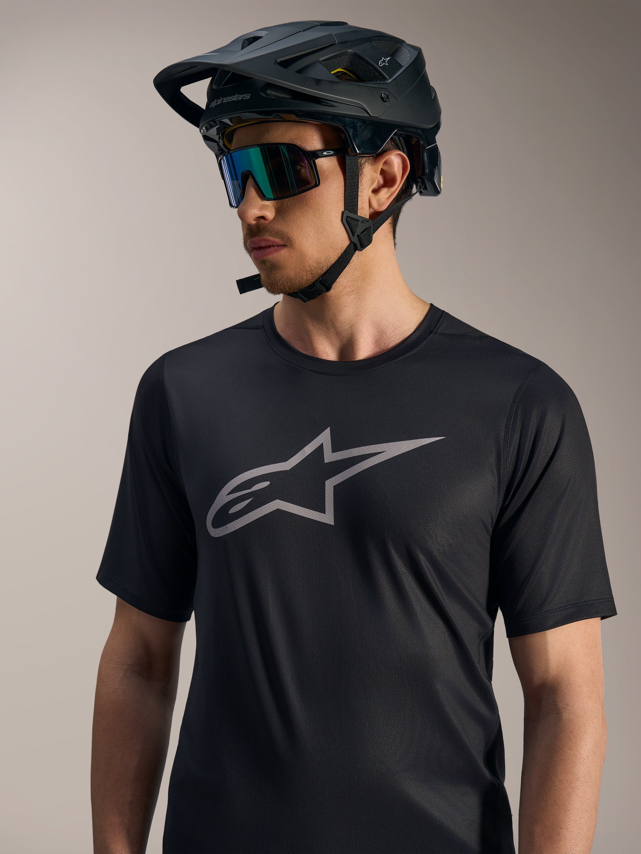 Alpinestars A-Dura Ride Short Sleeve Jersey in black with grey chest logo, styled with a mountain bike helmet and sunglasses.