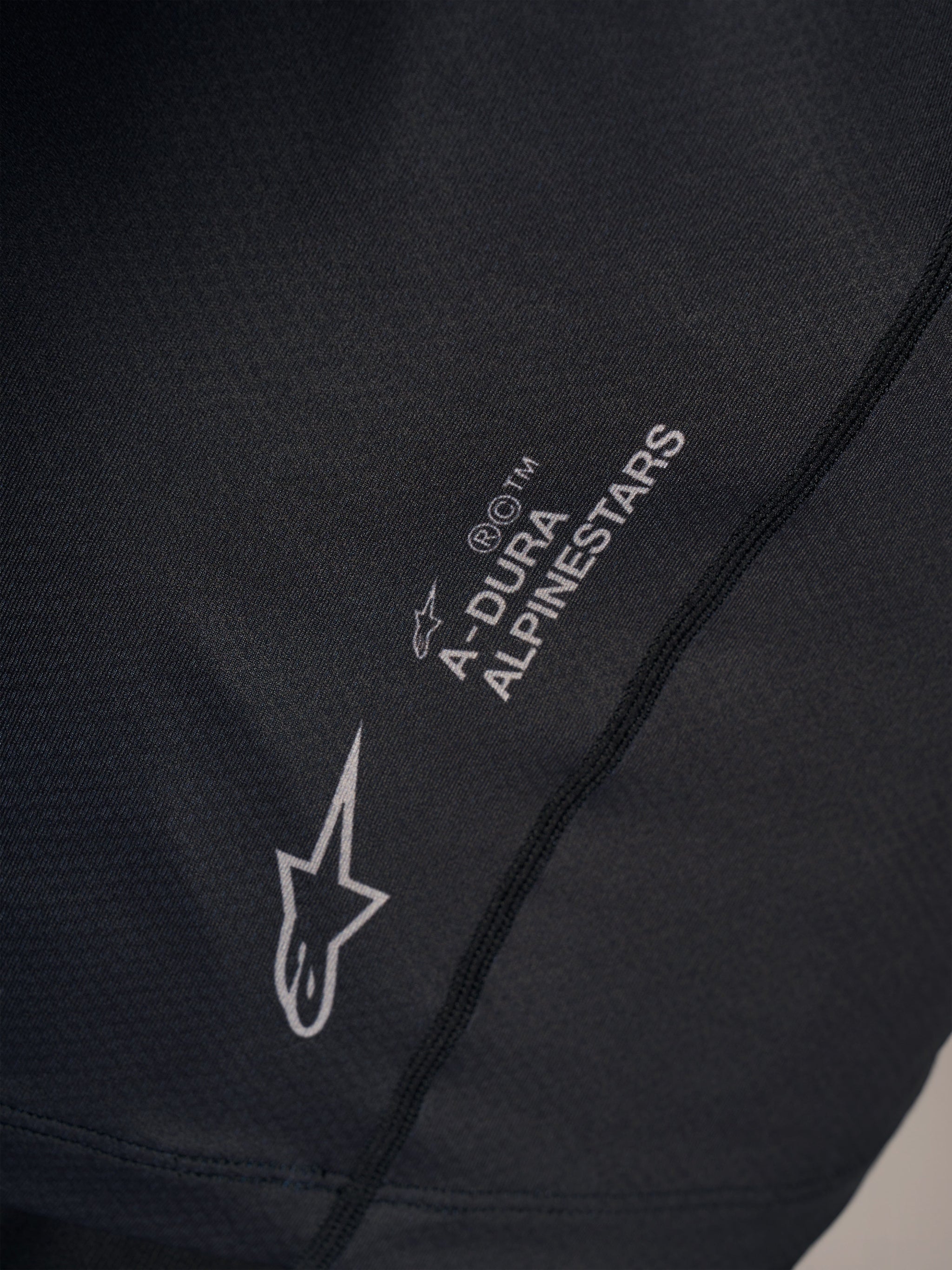 Black A-Dura Ride Short Sleeve Jersey detail featuring a silver Alpinestars logo and A-Dura wordmark on technical fabric.