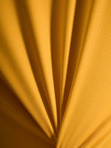 Close-up of orange A-Dura Ride Jersey fabric texture, showing the lightweight jacquard poly/spandex material.