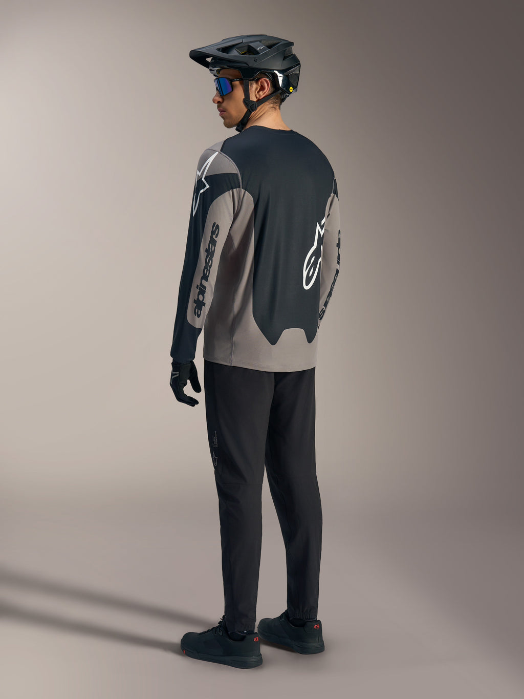 Maillot A-Dura Race à manches longues gris et noir Alpinestars, vu de dos dans une tenue de VTT complète.