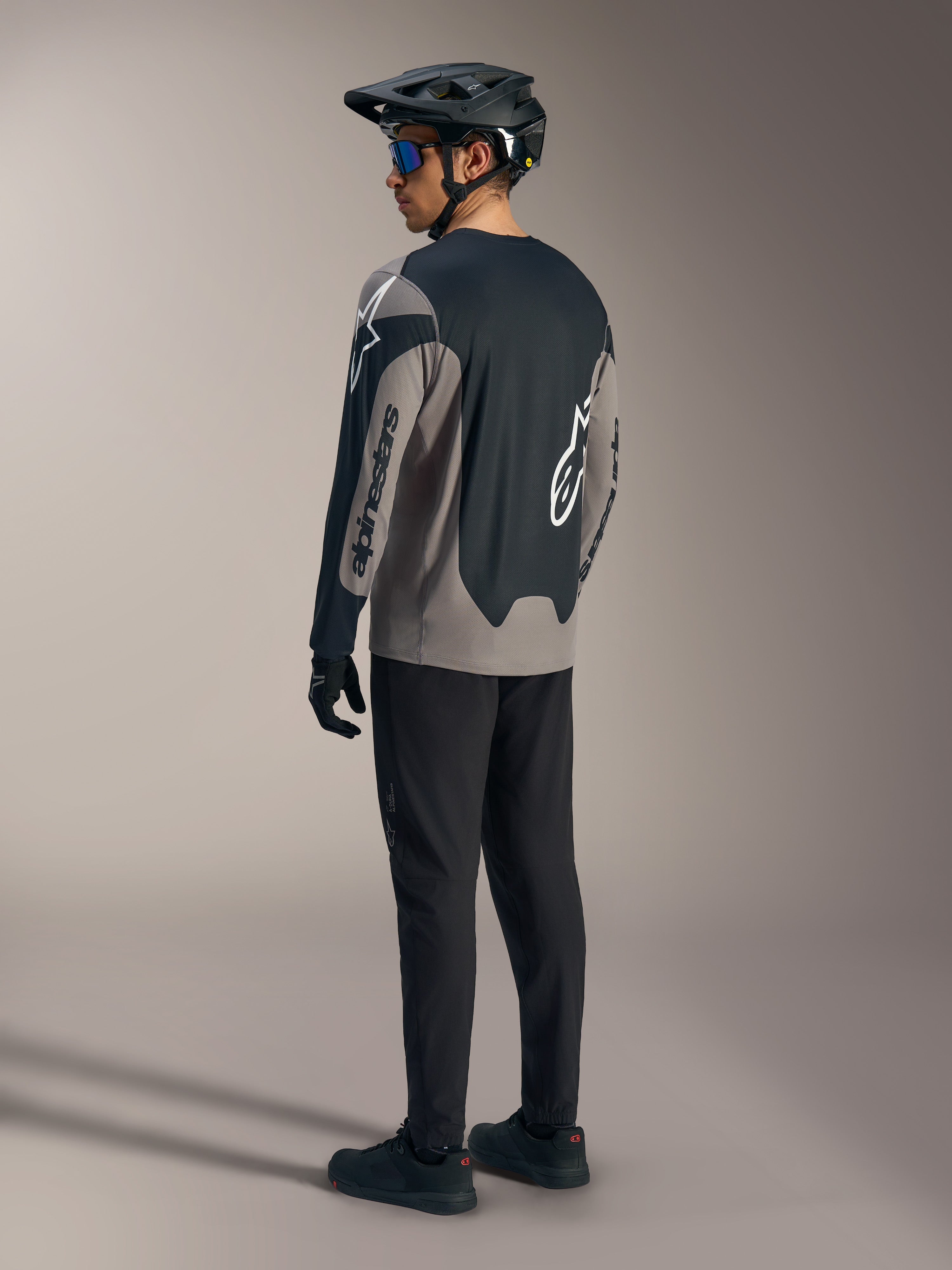 Maillot A-Dura Race à manches longues gris et noir Alpinestars, vu de dos dans une tenue de VTT complète.
