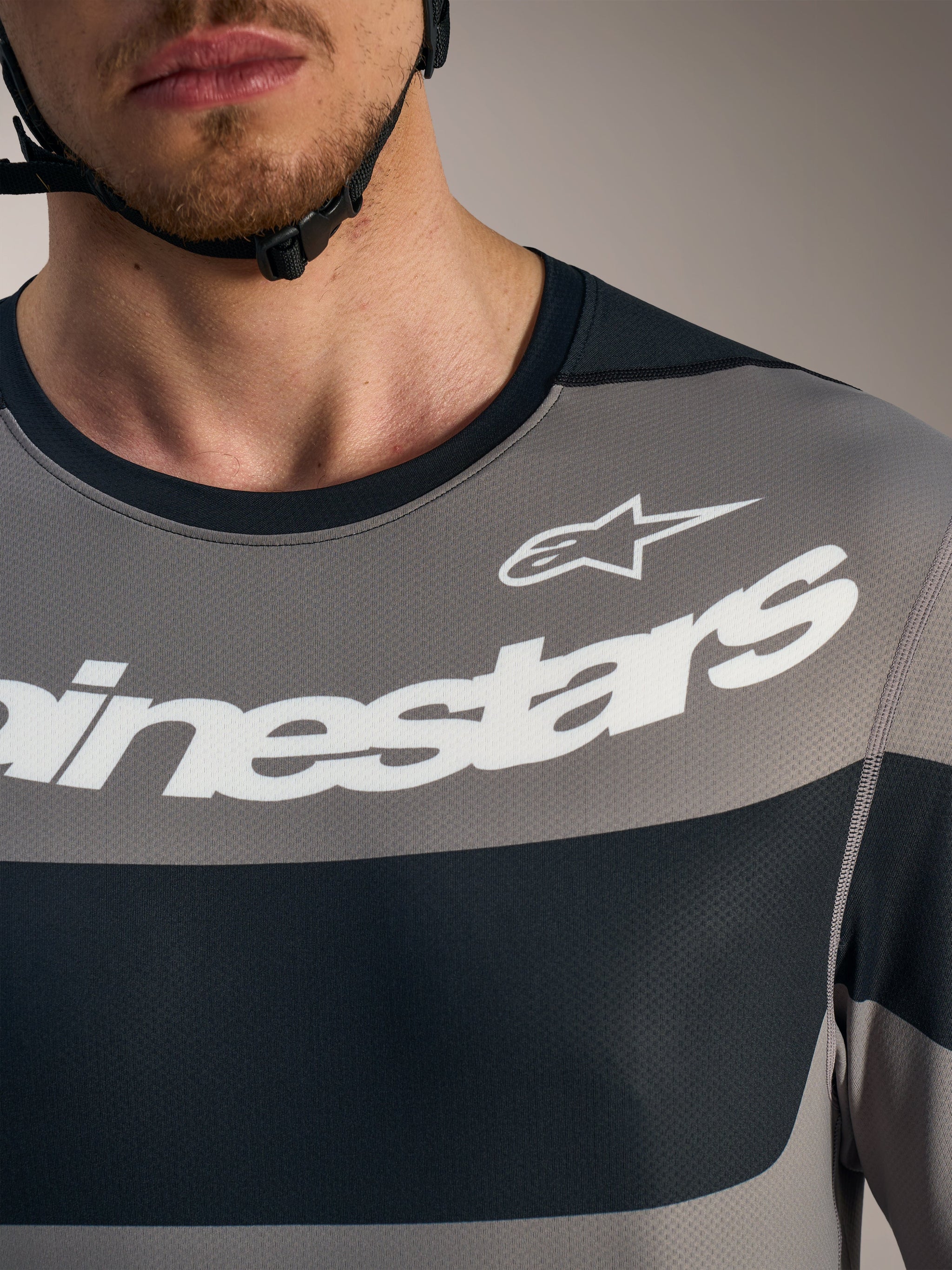 Détail poitrine du maillot A-Dura Race gris, logos Alpinestars blancs sur tissu technique en maille respirante.