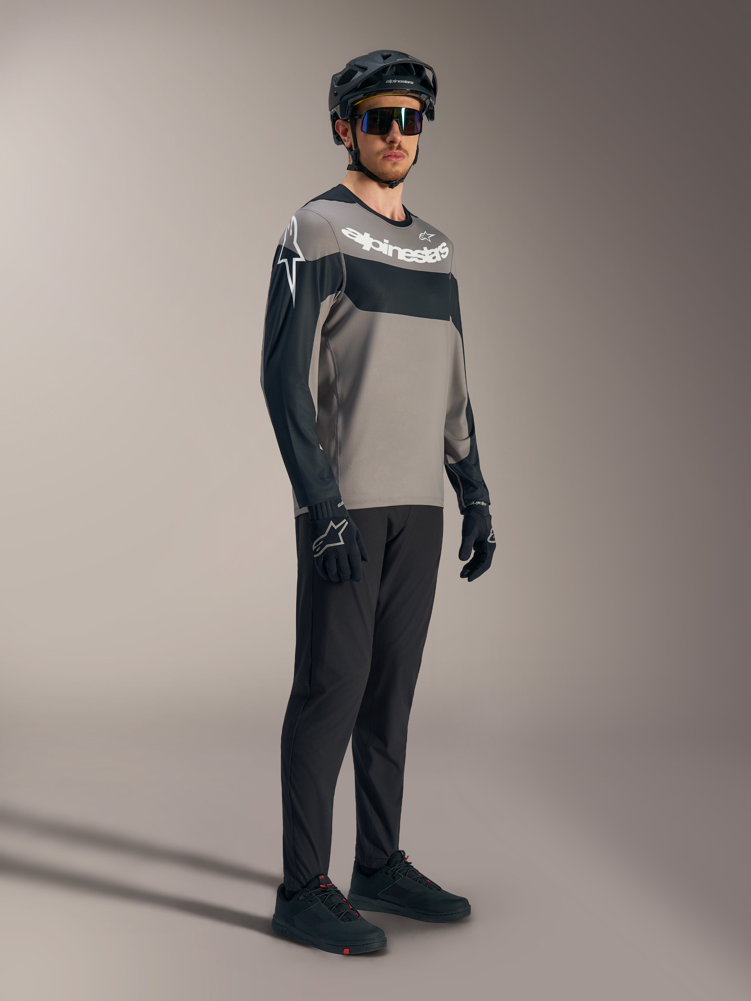 Maillot VTT A-Dura Race gris et noir à manches longues, logos blancs, avec pantalon de performance et casque.