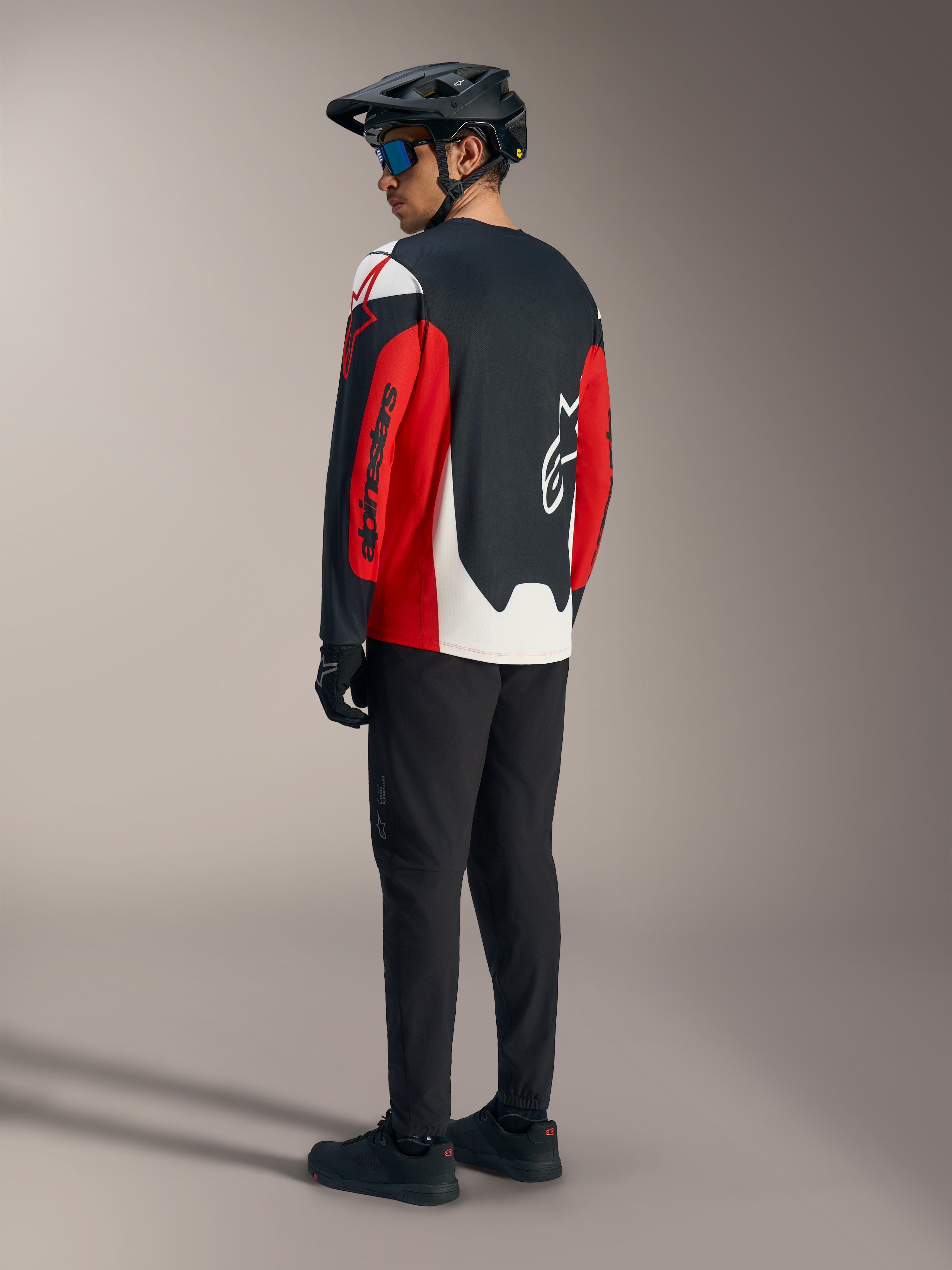 Maillot A-Dura Race rouge à manches longues, graphismes Alpinestars audacieux, vu de dos en tenue de VTT.