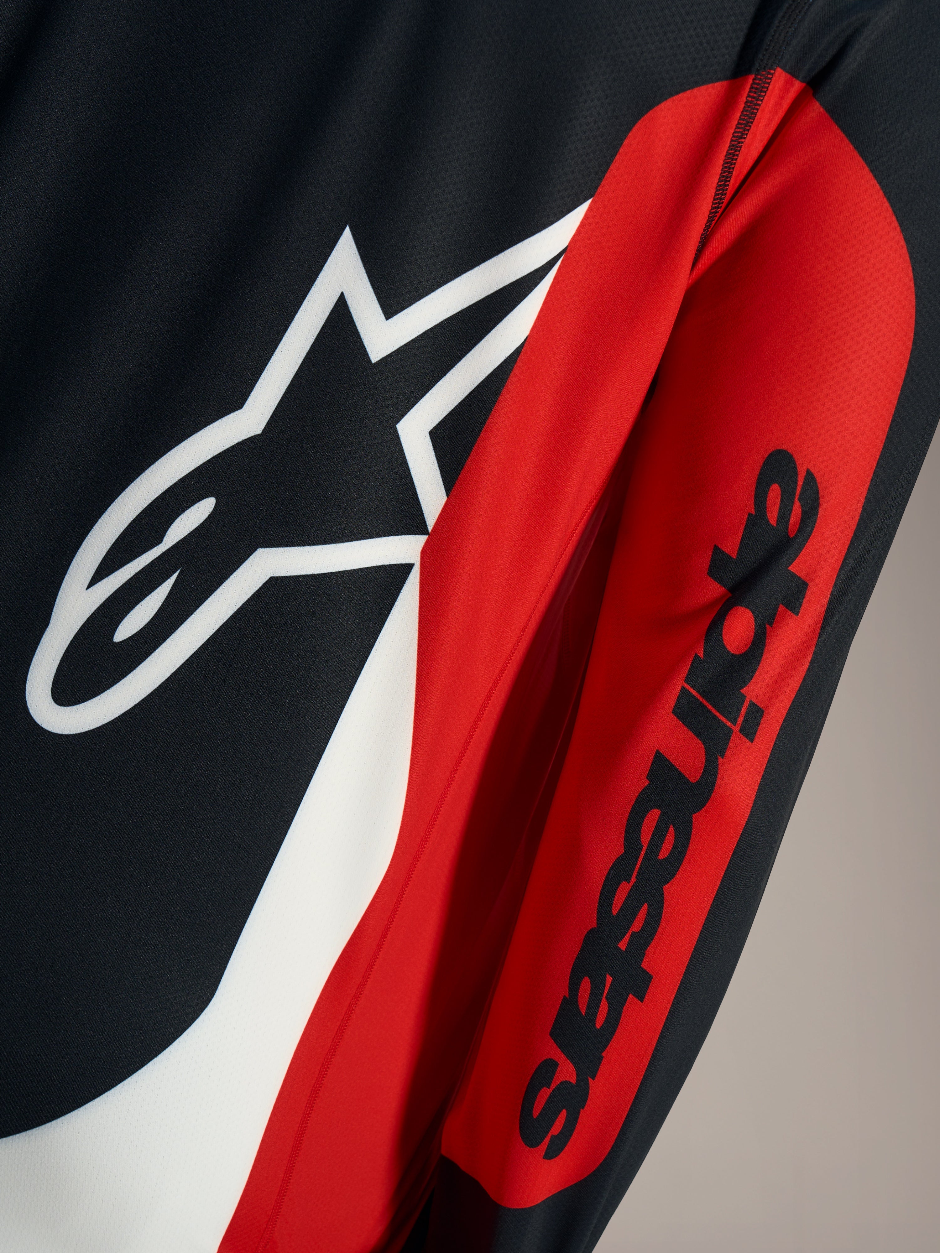 Détail du maillot A-Dura Race, logo Astars blanc et mot-symbole noir sur maille technique rouge et noire.