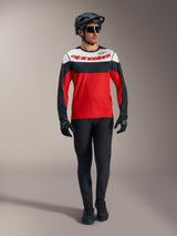 Maillot Alpinestars A-Dura Race rouge à manches longues, panneaux noirs et blancs, avec pantalon VTT et casque protecteur.