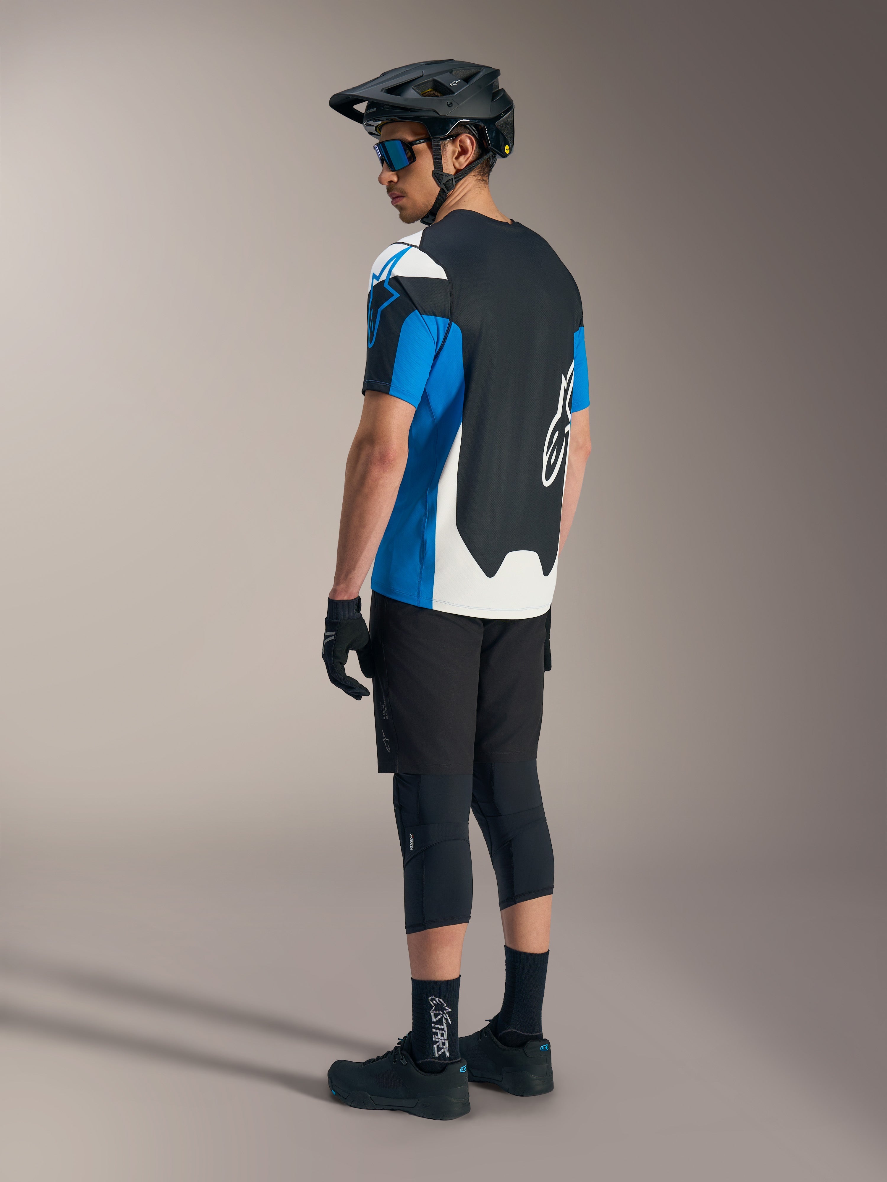 Maillot Alpinestars A-Dura Race SS bleu et noir, short de VTT noir, casque et équipement de protection.