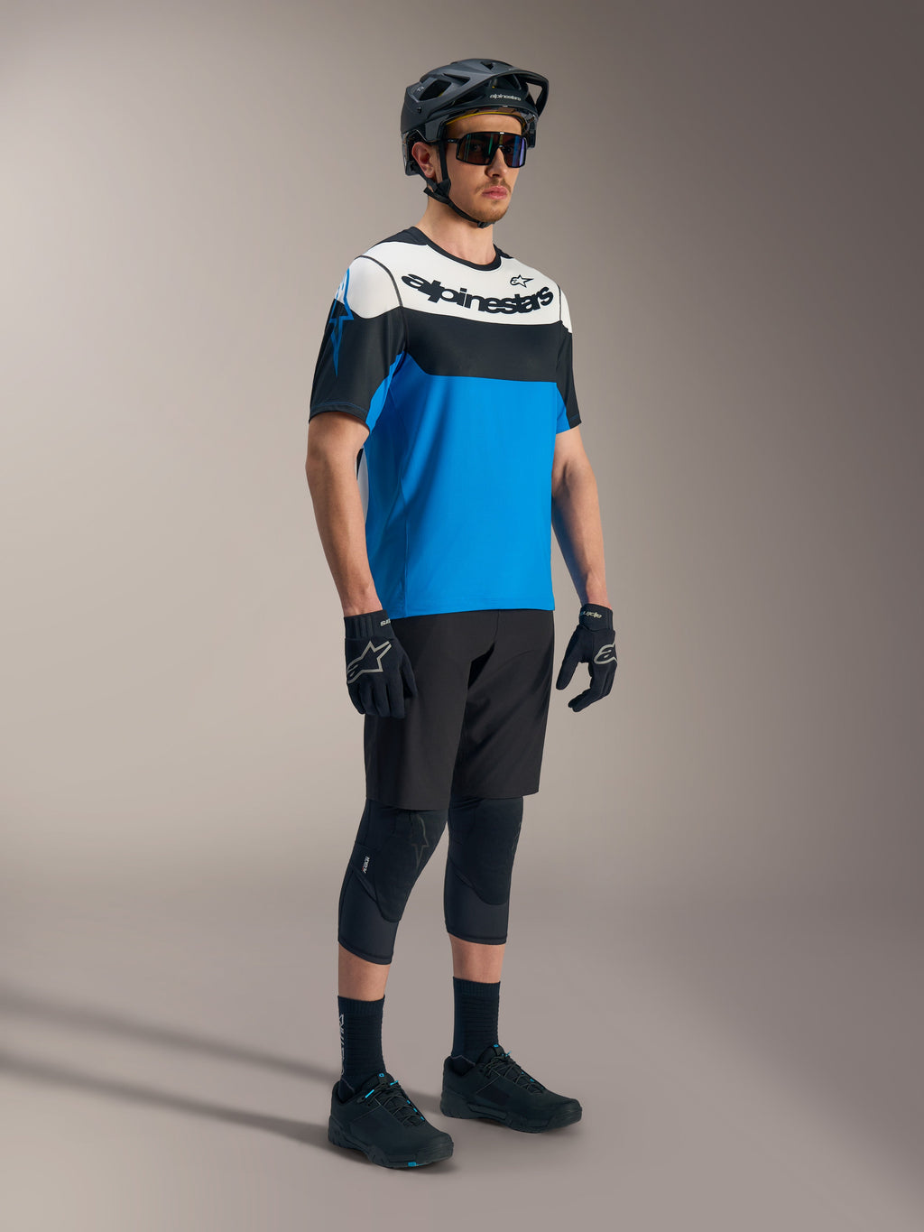 Maillot Alpinestars A-Dura Race SS bleu, noir et blanc, porté avec short A-Dura Ride et équipement de protection VTT.